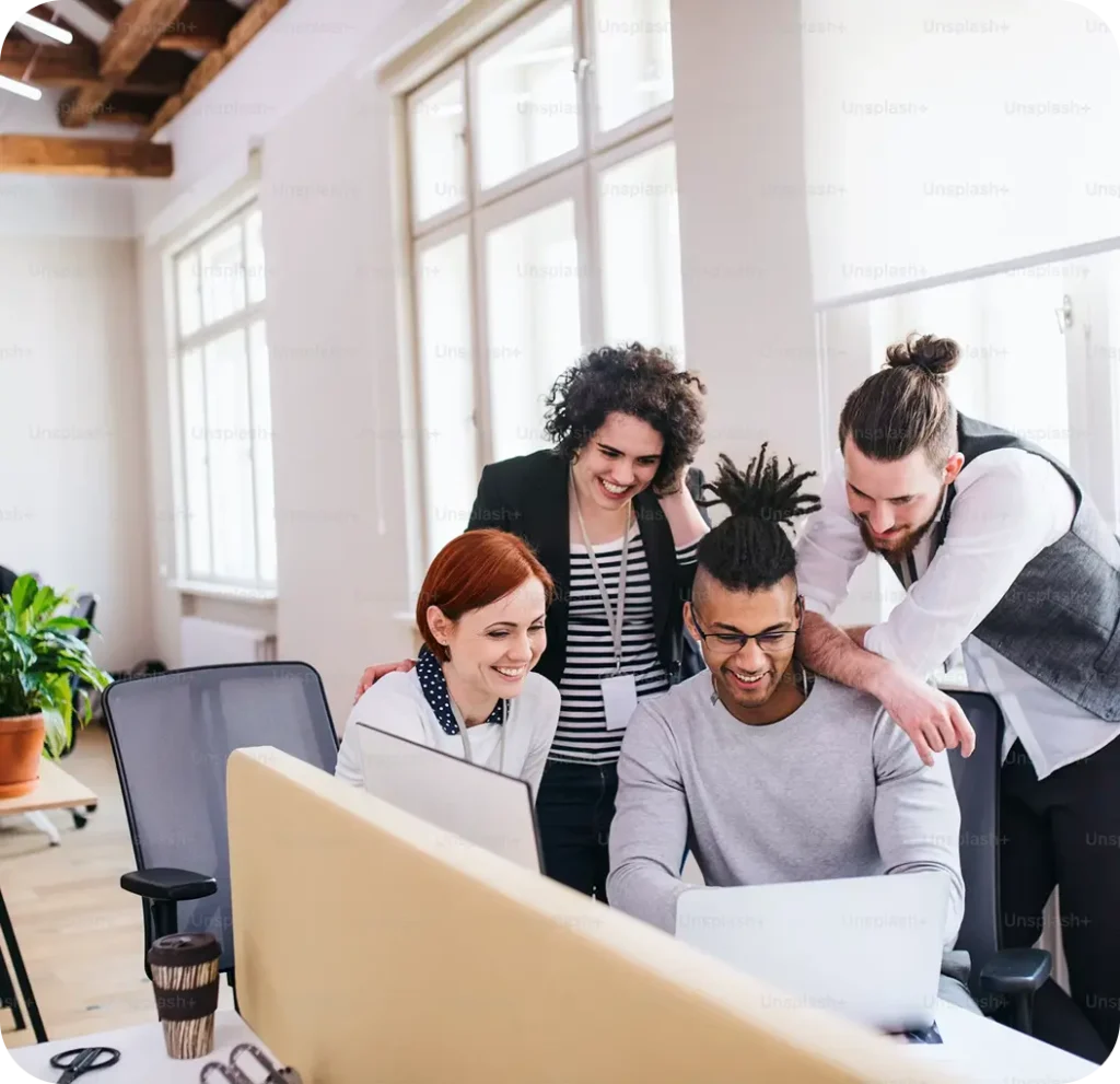 Een groep collega's werkt samen aan een laptop in een modern kantoor van Saleslift Studio.